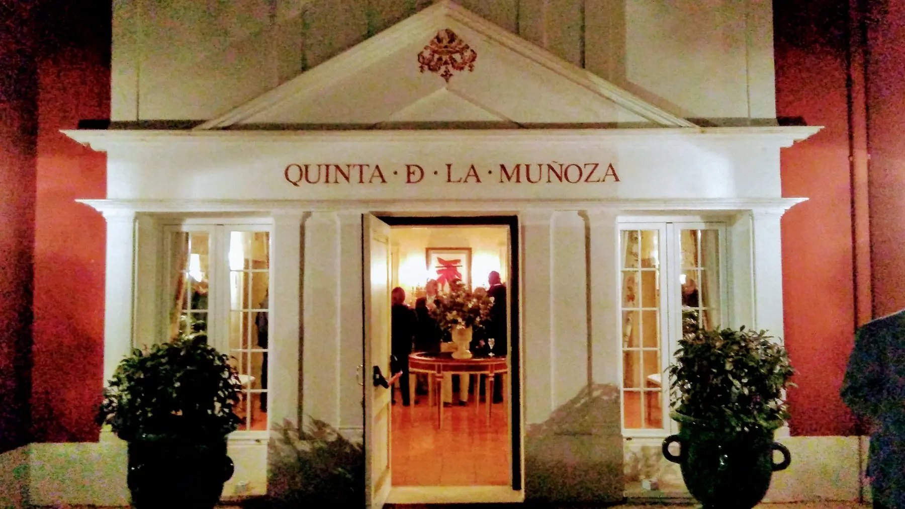 La puerta abierta de noche bajo el frontón: «Quinta de La Muñoza»