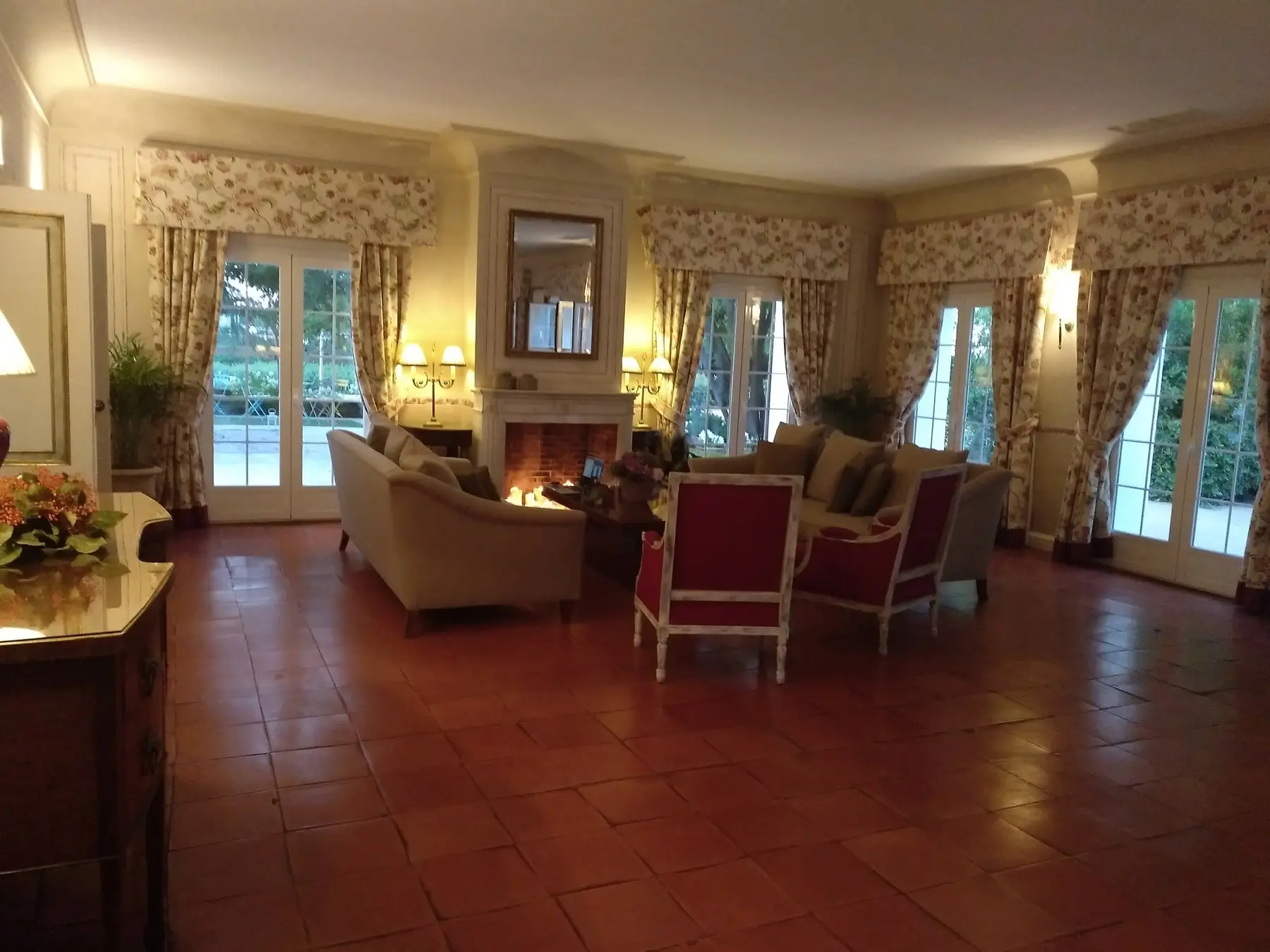 El salón con chimenea: sofás, butacas rojas y suelo de barro
